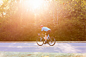 Radfahrer auf einer Straße mit hellem Sonnenlicht, das durch die Bäume bricht, in der Nähe der Trace Nachez Bridge; Franklin, Tennessee, Vereinigte Staaten von Amerika