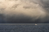 Stürmischer Himmel über dem Meer und ein Boot im offenen Wasser vor der Küste von South Shields; Tyne and Wear, England