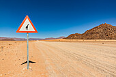 Attention wild animals sign on a long dry road, Namib Desert, Namib-Naukluft National Park; Namibia