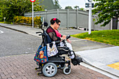 Maori woman with Cerebral Palsy in a wheelchair crossing a street; Wellington, New Zealand