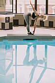 Frau trainiert auf einer Matte neben einem Schwimmbecken; Wellington, Neuseeland