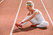 Woman ties her shoelace to prepare for running on a track; Wellington, New Zealand