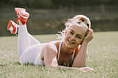 Young woman lying on a grass field in her workout wear; Wellington, New Zealand