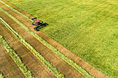 Aerial view of a swather cutting a barley field with graphic harvest lines; Beiseker, Alberta, Canada