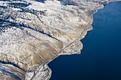 Eine abgelegene Küstenlinie mit blauem Ozeanwasser und kargem Land mit leichter Schneedecke entlang der Küste von British Columbia; British Columbia, Kanada