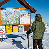 Abfahrtskifahrer vor einer Informationstafel und einer Karte im Sun Peaks Resort; Sun Peaks, British Columbia, Kanada