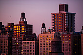 Residential buildings at dusk with HVAC unit and water reservoirs on the rooftops; New York City, New York, United States of America