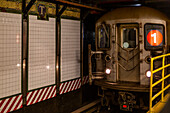 Subway underground on tracks beside tiled wall, Manhattan; New York City, New York, United States of America