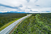 Die Berge bei Haines Junction im Sommer im Yukon. Radfahrer fahren auf dem Haines Highway während des jährlichen Radrennens von Haines nach Haines; Haines Junction, Yukon, Kanada