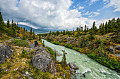 Eine Frau steht mit Blick auf den Tutshi River nahe der Grenze zwischen Yukon und British Columbia; Yukon, Kanada