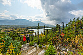 Two women stand on a rock overlooking the landscape of Wright Pass near the Canada/USA border; Yukon, Canada