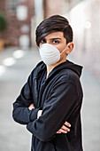 Pre-teen boy stands wearing a protective mask to protect against COVID-19 during the Coronavirus World Pandemic; Toronto, Ontario, Canada
