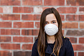 Young girl stands wearing a protective mask to protect against COVID-19 during the Coronavirus World Pandemic; Toronto, Ontario, Canada