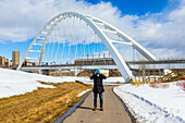 A man wearing a mask and gloves stands on a path outside holding his head in his hands in fear during the Covid-19 world pandemic; Edmonton, Alberta, Canada