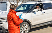 Two women meet in the neighbourhood during the Covid-19 world pandemic, physical distancing with one woman in her car and one woman on the street; St. Albert, Alberta, Canada