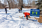 Familien stehen während der Covid-19-Weltpandemie auf einem Weg durch einen Park, um sich zu besuchen; St. Albert, Alberta, Kanada