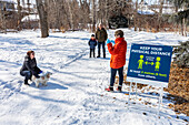 Familien stehen während der Covid-19-Weltpandemie in einiger Entfernung auf einem Weg durch einen Park zu Besuch; St. Albert, Alberta, Kanada