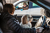 Two women meet in the neighbourhood during the Covid-19 world pandemic, physical distancing from their vehicles on the street; St. Albert, Alberta, Canada