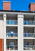 A woman stands on her balcony getting fresh air during isolation, Covid-19 world pandemic; St. Albert, Alberta, Canada