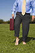 Businessman Walking Barefoot on Grass