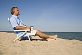 Mann entspannt sich am Strand mit einer Tasse Kaffee, Lake Michigan, USA