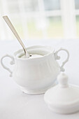 White porcelain sugar bowl with sugar and spoon, studio shot