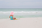 Back View of Toddler Girl wearing Sunhat on Beach looking out at Ocean, Destin, Florida, USA