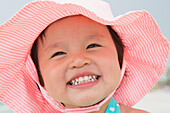 Nahaufnahme eines kleinen Mädchens mit Sonnenhut und Lächeln am Strand, Destin, Florida, USA
