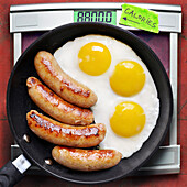 Overhead View of Greasy Fried Eggs and Sausage in Frying Pan with Scale