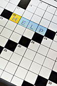 Close-up of crossword puzzle on LCD tablet screen, showing the word help, studio shot