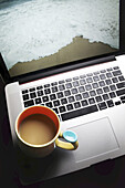 Kaffeetasse auf Laptop-Computer mit Strand auf dem Bildschirm