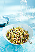 Pasta Salad in Large Bowl with Serving Spoon and Glassware on Blue Tablecloth in Studio