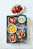 Variety of condiments in small bowls on metal tray, studio shot
