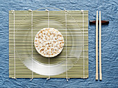 Draufsicht auf Reiskuchen auf Teller mit Stäbchen, Studioaufnahme