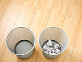 Overhead view of empty and used waste baskets on wooden floor, studio shot