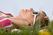 Woman Lying Down in Meadow, Listening to Music