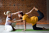 Yogalehrer mit Schüler, der die Tiger-Pose einnimmt