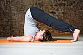 Frau im Yogakurs in Pflugstellung