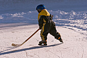 Kleiner Junge spielt Eishockey auf einem gefrorenen Teich, Fuschlsee, Salzburger Land, Österreich