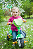 Kleines Mädchen fährt auf einem dreirädrigen Fahrrad