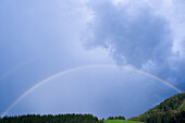 Regenbogen über Feld und Bäumen, Salzburg, Österreich