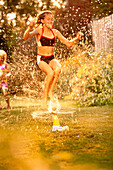 Mädchen in Badekleidung, Springen durch Sprinkler