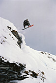 Snowboarder springt über einen Hügel, Jungfrau Region, Schweiz