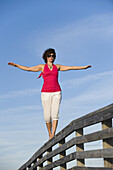 Frau balanciert auf einem Holzgeländer, Honeymoon Island State Park, Florida, USA