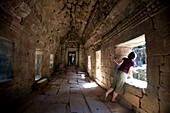 Tourist schaut durch Tempelfenster in der antiken Stadt Angkor; Angkor Wat, Siem Reap, Kambodscha