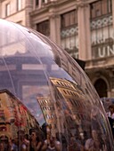Nahaufnahme einer Glaskugel mit Menschen und Gebäuden, die sich darin spiegeln; Rom, Italien