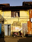 Scooter lehnt gegen ein verfallenes Haus auf einer leeren Straße; Jewtown, Cochin, Kerala, Indien