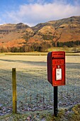 Roter Briefkasten am Straßenrand, Felder im Hintergrund; Cumbria, England, UK
