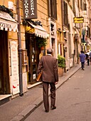 Rückansicht eines älteren Mannes, der auf der Straße geht und eine Aktentasche trägt; Rom, Italien