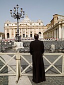 Rear View Of Priest Watching St. Peter's Square; Rome, Italy